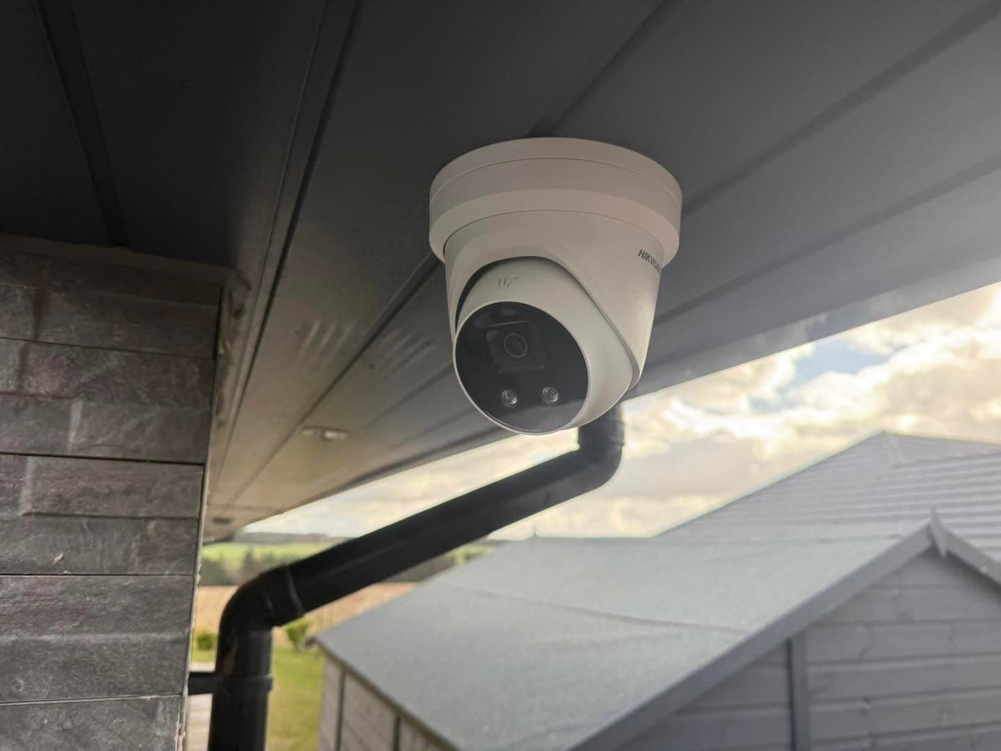 Hikvision CCTV camera mounted under a soffit overlooking open Lanarkshire countryside