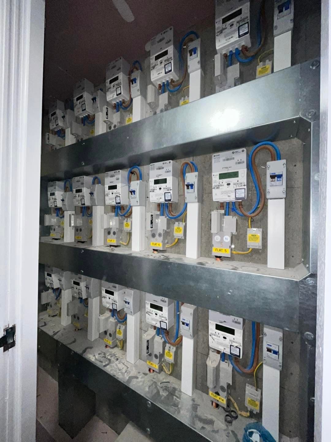 Bank of labelled electricity meters and isolators for a multi-flat development, installed and wired by Gunning