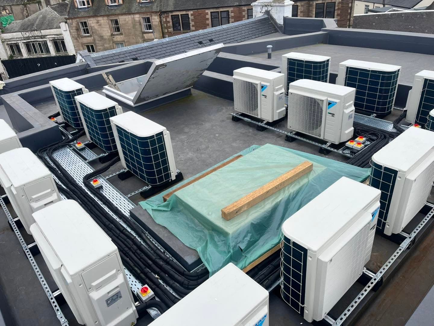 Large rooftop plant installation with air conditioning condensers, cable tray and isolators on a commercial building